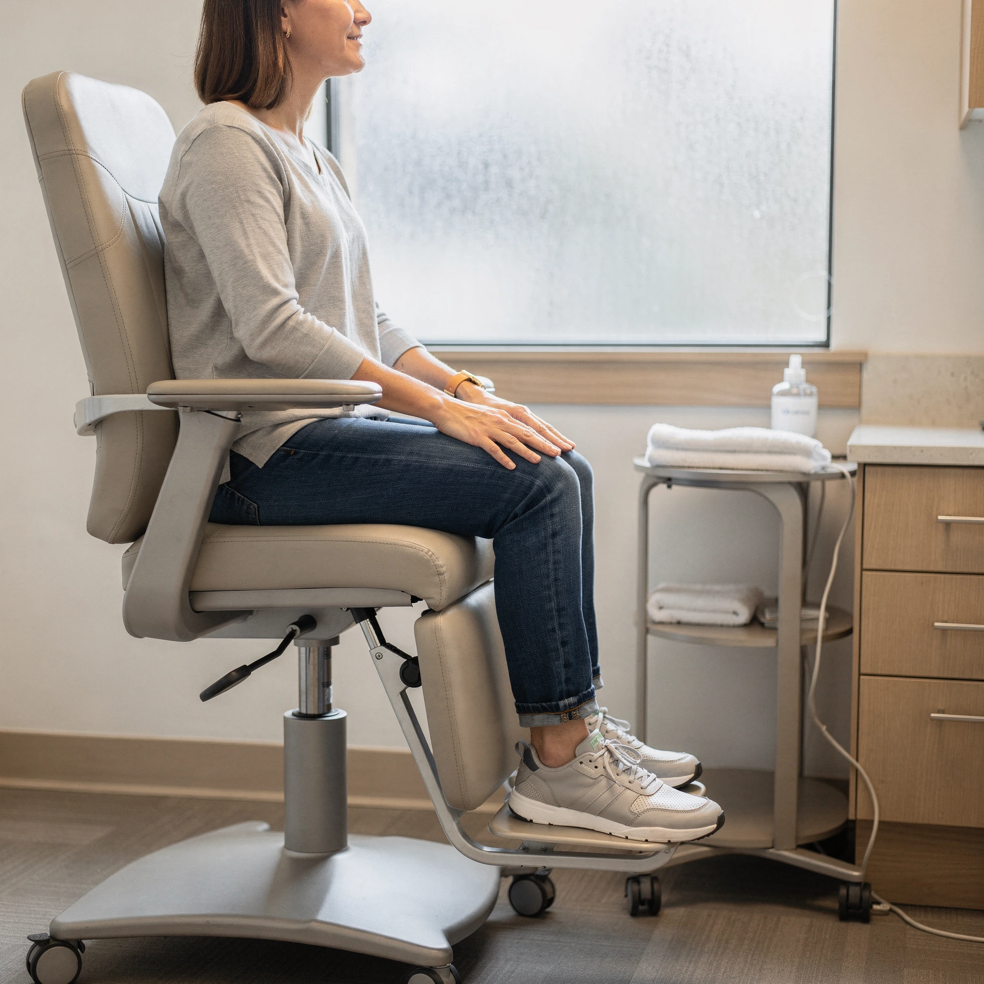 Patient seated in exam chair with foot positioned on footrest in podiatry clinic examination room
